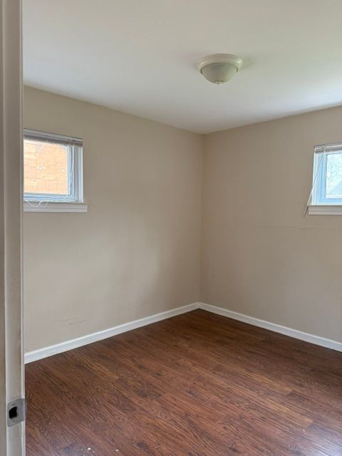 unfurnished room with baseboards and dark wood-type flooring