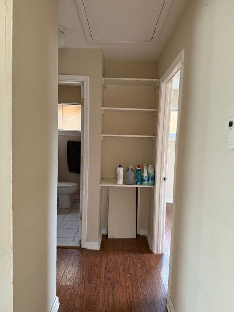 corridor with baseboards, attic access, and wood finished floors