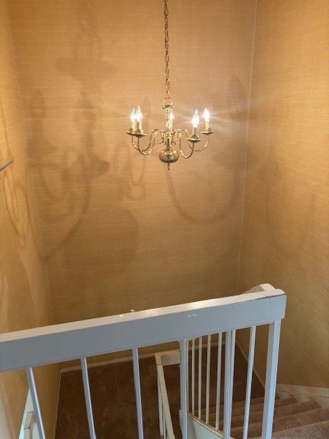 stairs with a notable chandelier