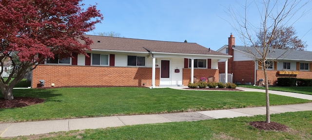 ranch-style home featuring a chimney, a front yard, and brick siding
