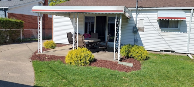 exterior space featuring fence, a shingled roof, a lawn, and a patio