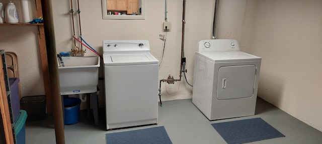 washroom featuring washing machine and clothes dryer, laundry area, and a sink