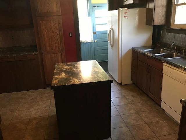 kitchen featuring a sink, tasteful backsplash, a kitchen island, white appliances, and dark countertops