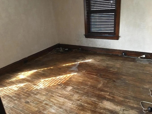 empty room featuring hardwood / wood-style flooring and baseboards