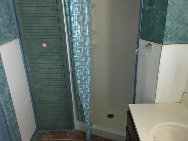 full bathroom with a stall shower, tile patterned flooring, vanity, and baseboards