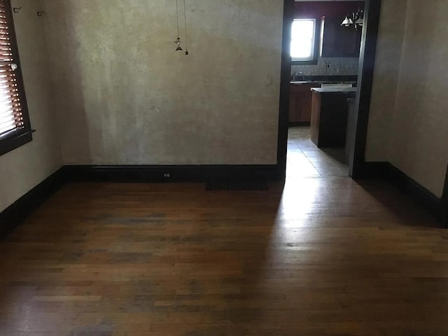 unfurnished dining area featuring baseboards, light wood finished floors, and a sink