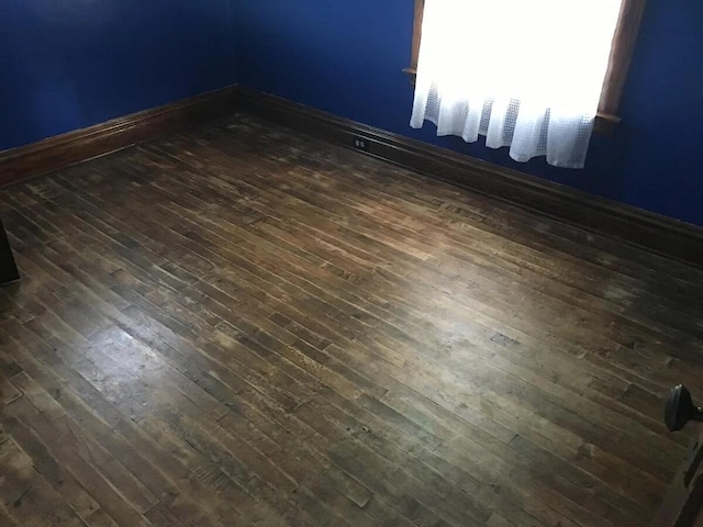 spare room with dark wood finished floors and baseboards