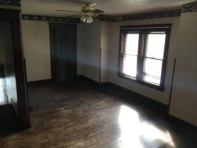 spare room with dark wood finished floors and ceiling fan