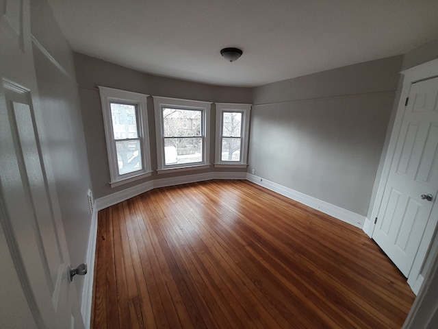 unfurnished room featuring baseboards, hardwood / wood-style flooring, and a wealth of natural light