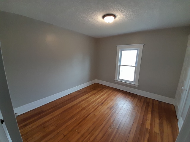 unfurnished room with baseboards, a textured ceiling, and hardwood / wood-style floors