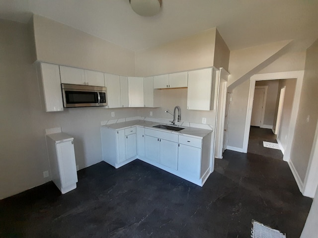 728 W Philadelphia St, Detroit, MI 48202 - kitchen featuring a sink, stainless steel microwave, white cabinetry, light countertops, and concrete floors