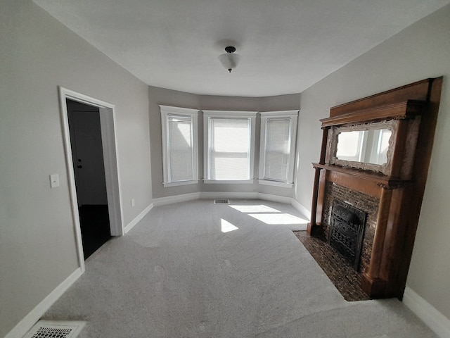 unfurnished living room with carpet floors, baseboards, visible vents, and a tile fireplace