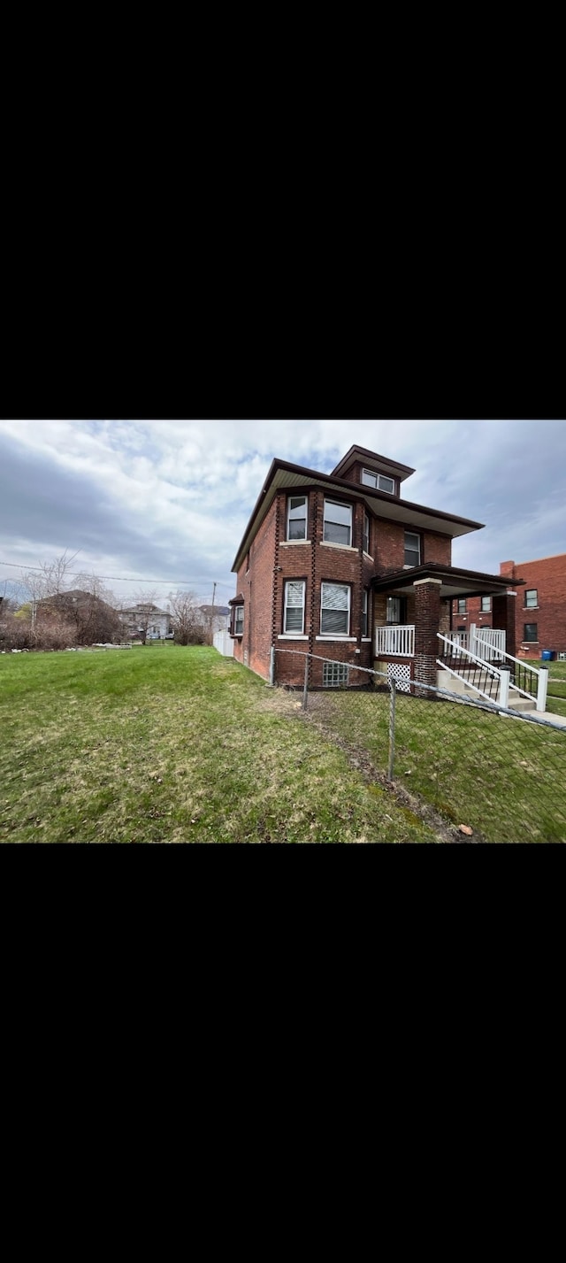 rear view of house featuring brick siding and a yard