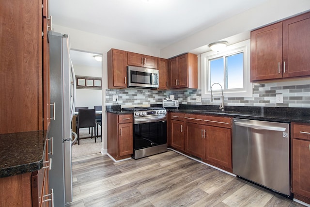 kitchen featuring a sink, light wood finished floors, appliances with stainless steel finishes, and decorative backsplash