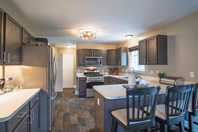 8313 Mill Pointe Ct, Goodrich, MI 48438 - kitchen featuring appliances with stainless steel finishes, a peninsula, a sink, dark wood-style flooring, and light countertops
