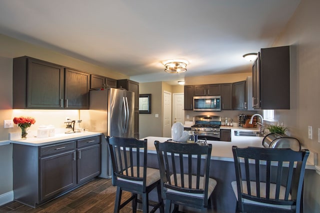 8313 Mill Pointe Ct, Goodrich, MI 48438 - kitchen featuring stainless steel appliances, a sink, a peninsula, dark wood-style flooring, and light countertops