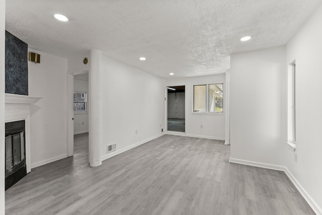unfurnished living room featuring recessed lighting, a large fireplace, visible vents, a textured ceiling, and wood finished floors