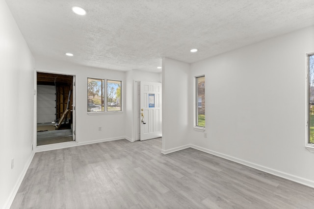 interior space with a textured ceiling, wood finished floors, recessed lighting, and baseboards