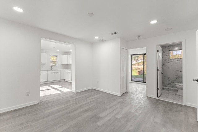 unfurnished living room with visible vents, recessed lighting, light wood finished floors, and a sink