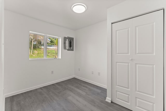 unfurnished bedroom featuring wood finished floors, electric panel, and baseboards