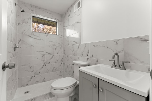 full bath featuring tile walls, visible vents, a shower stall, and vanity