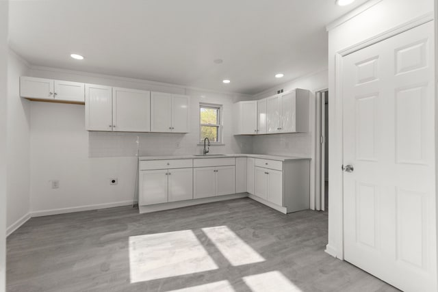 kitchen featuring backsplash, recessed lighting, white cabinets, and a sink