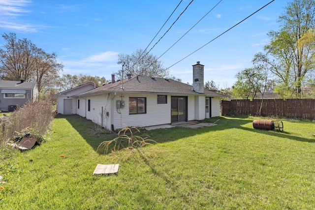 rear view of property with a yard, a chimney, and fence