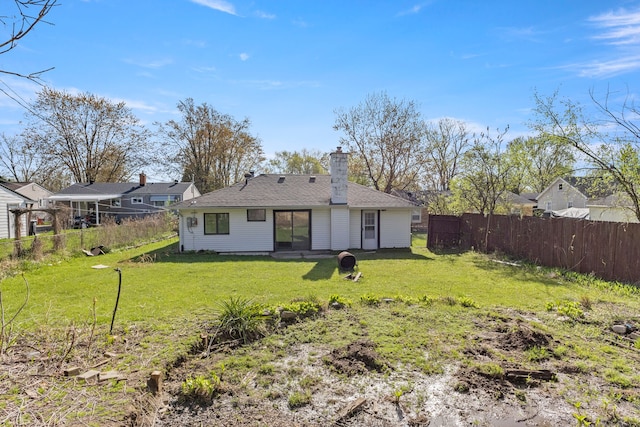 back of house with a chimney, fence, and a lawn