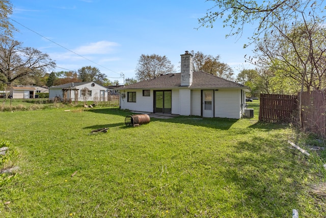 rear view of property with a chimney, fence, and a yard