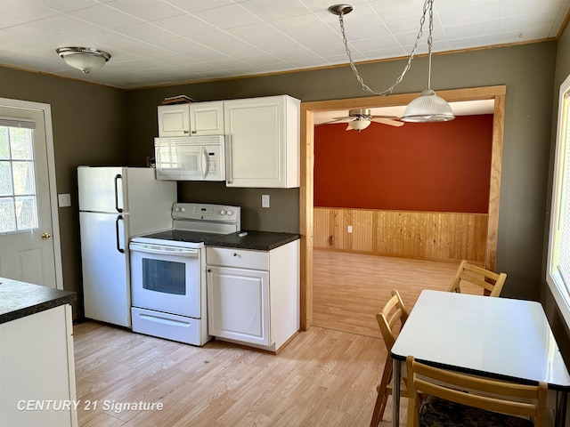 kitchen with light wood-style flooring, wood walls, white cabinetry, and white appliances