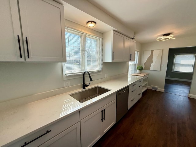 kitchen featuring a sink, dishwasher, dark wood finished floors, white cabinetry, and baseboards