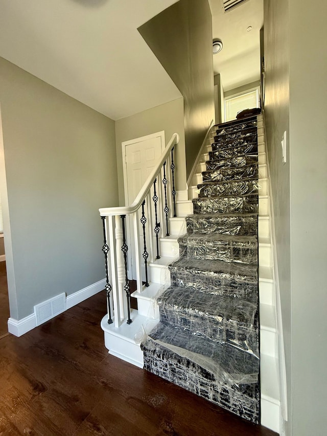 stairs featuring visible vents, baseboards, and wood finished floors