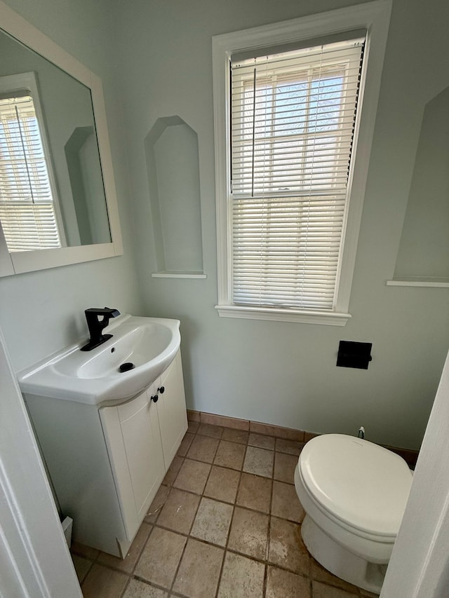 bathroom with toilet, baseboards, and vanity