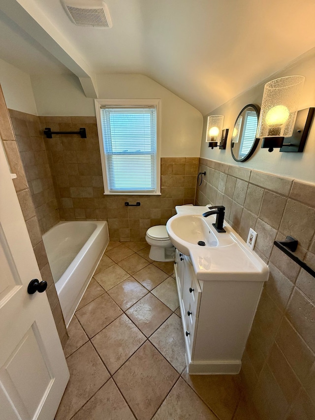 bathroom with visible vents, lofted ceiling, tile patterned flooring, and tile walls