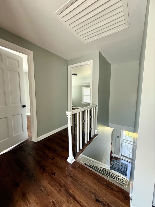 stairs with baseboards, wood finished floors, and visible vents