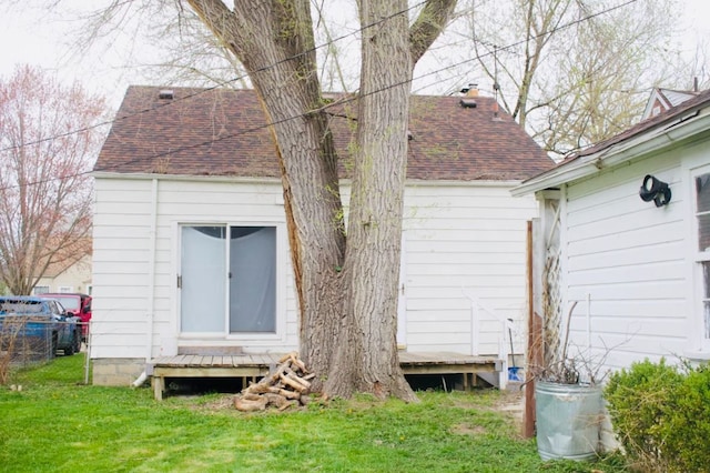 back of property with a yard, fence, and a shingled roof