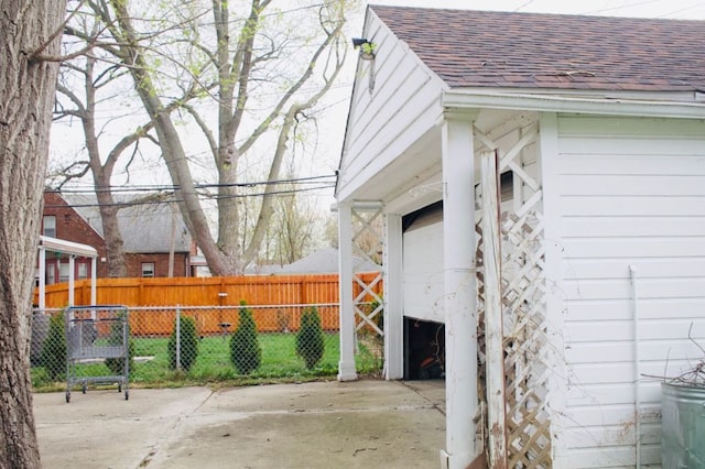 view of side of home with a shingled roof and fence