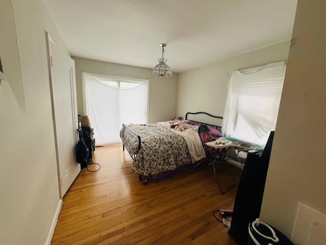 bedroom featuring baseboards, hardwood / wood-style flooring, and a notable chandelier