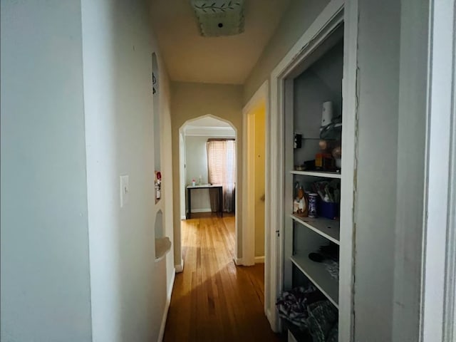 corridor featuring arched walkways and dark wood-style floors
