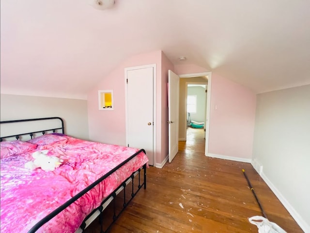 bedroom with baseboards, lofted ceiling, and hardwood / wood-style flooring