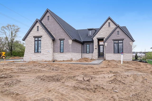 view of front of property featuring roof with shingles and stone siding