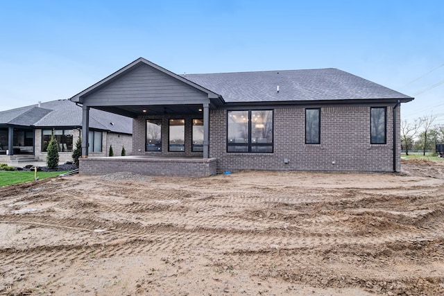 back of property featuring brick siding and a shingled roof