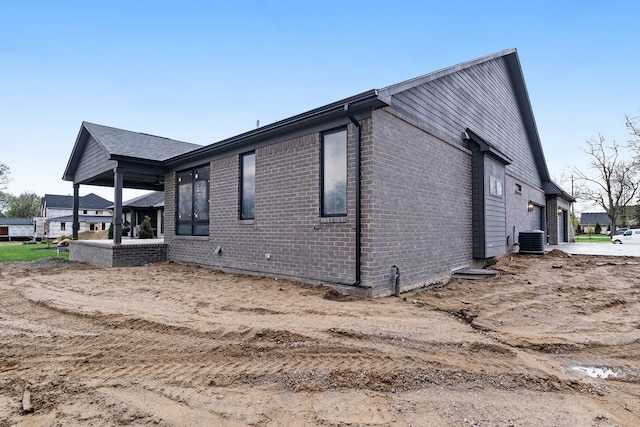 view of side of home featuring a garage, cooling unit, and brick siding
