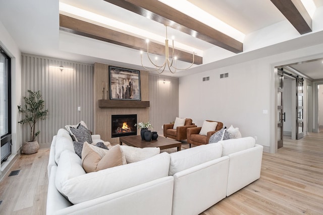 living area featuring visible vents, a barn door, and light wood-style floors