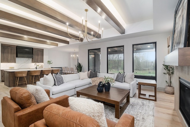 living area with an inviting chandelier, light wood-style floors, beam ceiling, and a fireplace