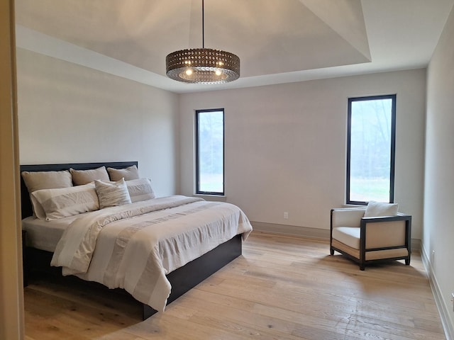 bedroom with light wood-type flooring, baseboards, and multiple windows