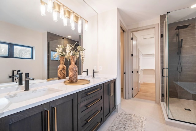 bathroom featuring double vanity, tile patterned floors, a shower stall, and a sink