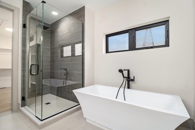 bathroom with recessed lighting, a spacious closet, a shower stall, and a freestanding bath