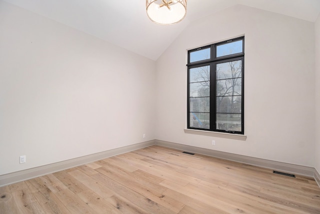 unfurnished room featuring baseboards, vaulted ceiling, light wood finished floors, and visible vents