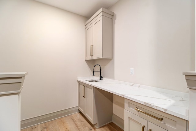 bar featuring a sink, baseboards, and light wood-style floors